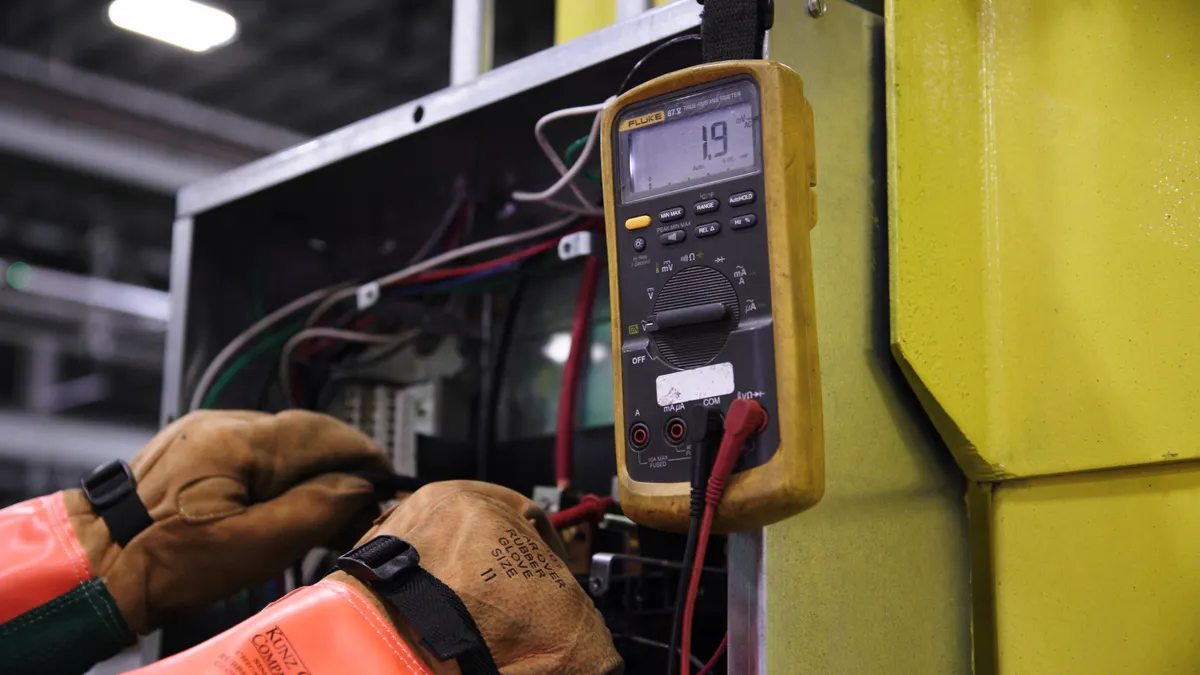 Technician testing inside an electrical cabinet with a multimeter