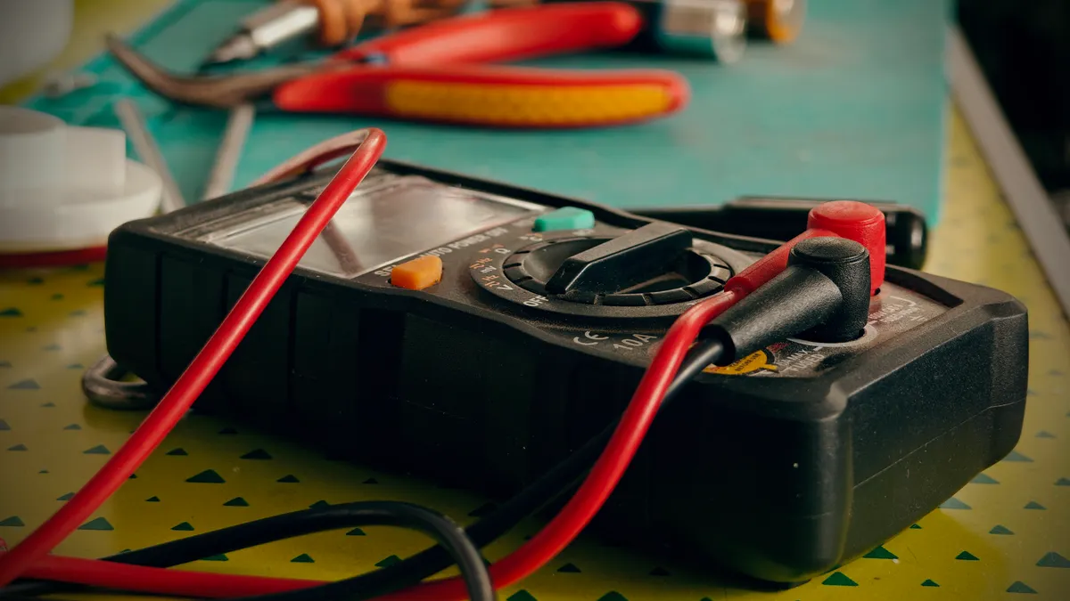 Multimeter with red and black probes on a workbench